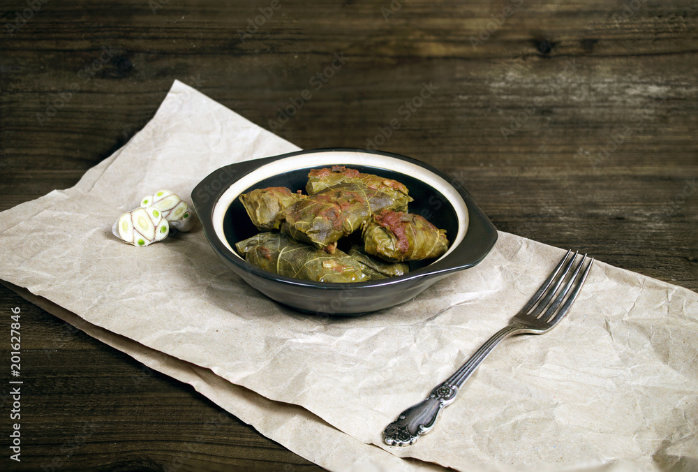 Mediterranean dish dolma rice with meat wrapped in grape leaves, fork and garlic Mediterranean dish dolma rice with meat wrapped in grape leaves, fork and garlic