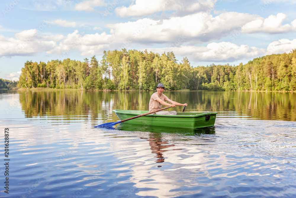 Fisherman with fishing rods is fishing in a wooden boat against background of beautiful nature and lake or river. Camping tourism relax trip active lifestyle adventure concept Fisherman with fishing rods is fishing in a wooden boat against background of beautiful nature and lake or river. Camping tourism relax trip active lifestyle adventure concept