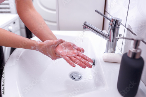 Hand cleaning with soap in bathroom under running water Close up.