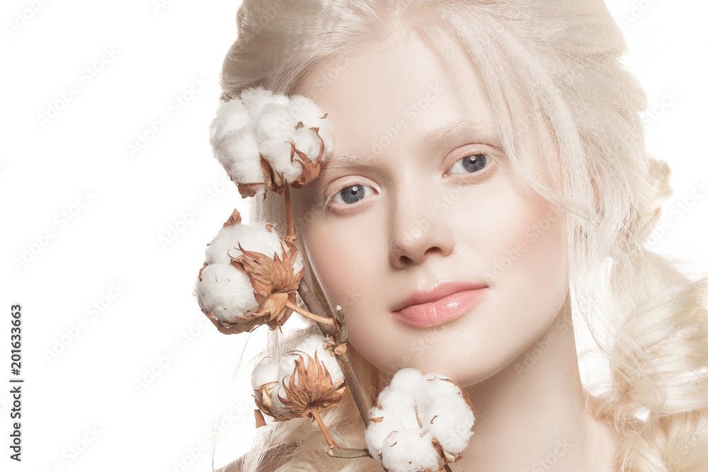 very delicate portrait of a young girl on a white background. Hair braid and natural make-up. Cotton flowers in the hands. The portrait is taken in the studio. very delicate portrait of a young girl on a white background. Hair braid and natural make-up. Cotton flowers in the hands. The portrait is taken in the studio.