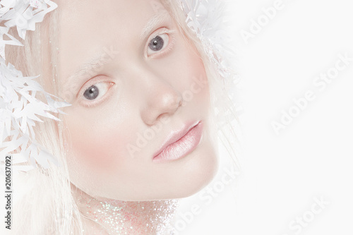 A very delicate portrait of an albino girl, a white background, snowflakes in her hair, sparkles, a magical winter image. Natural make-up, pink lipstick on lips.
