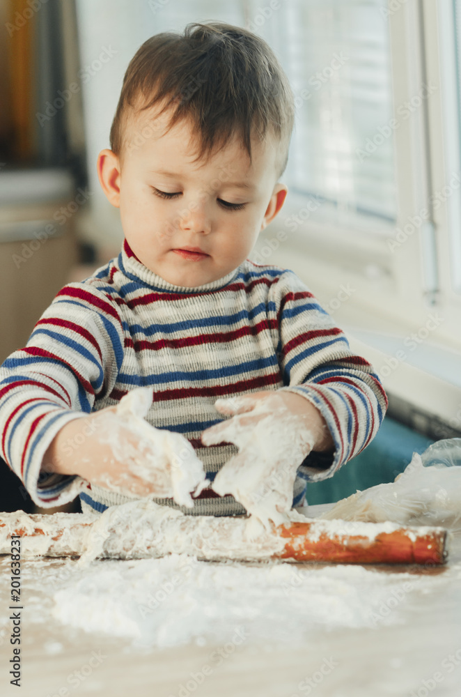 Fototapeta premium the child makes dough from flour house kitchen, played with the little chef
