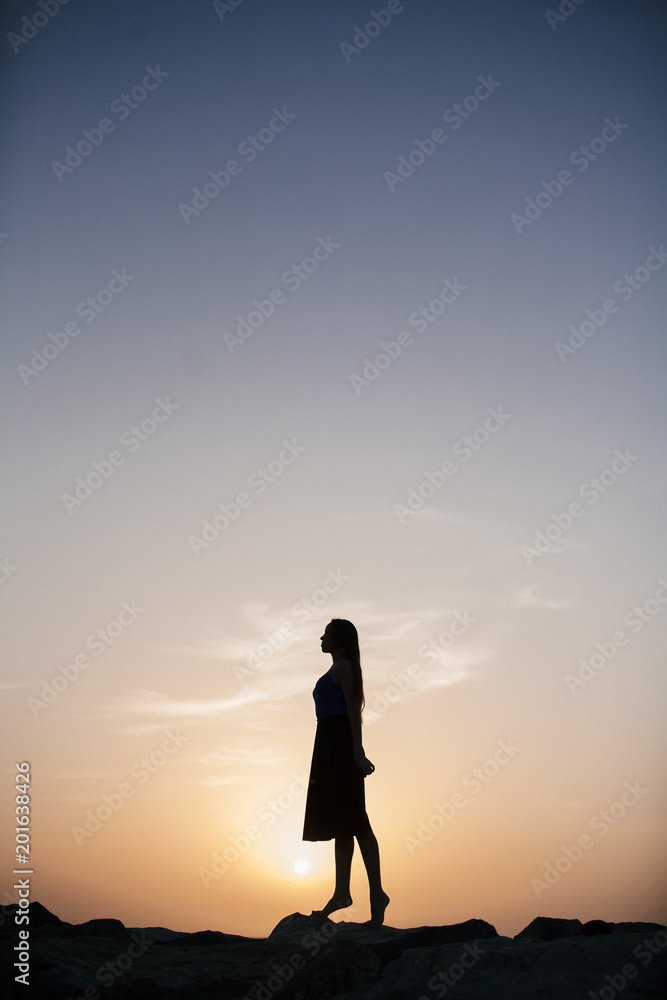 Fototapeta premium Beautiful girl on a sunset background on a sandy beach