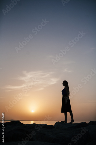 Beautiful girl on a sunset background on a sandy beach