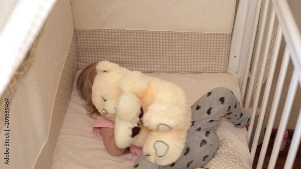child is playing with a teddy bear in the bedroom. child is playing with a teddy bear in the bedroom.