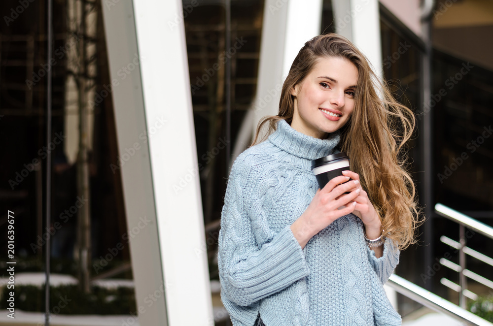 Young attractive lady with long curly hair with coffee to go, wearing stylish clothes 