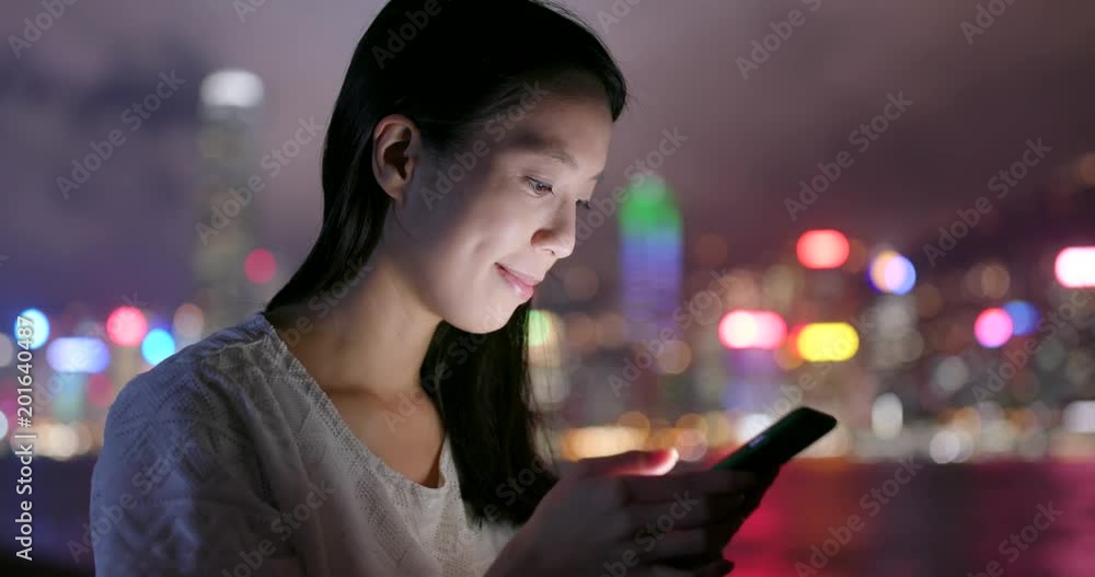 Woman use of cellphone for sending audio message in Hong Kong at night Woman use of cellphone for sending audio message in Hong Kong at night