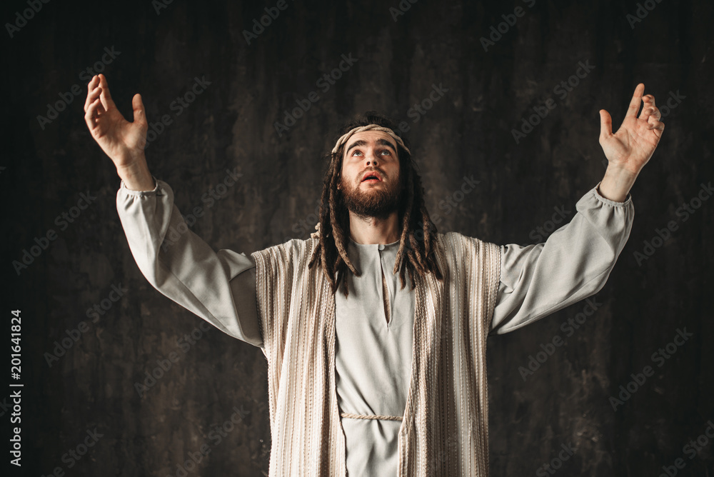 Jesus Christ in white robe prays with his hands up ภาพถ่ายสต็อก Adobe