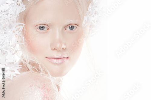 A very delicate portrait of an albino girl, a white background, snowflakes in her hair, sparkles, a magical winter image. Natural make-up, pink lipstick on lips.