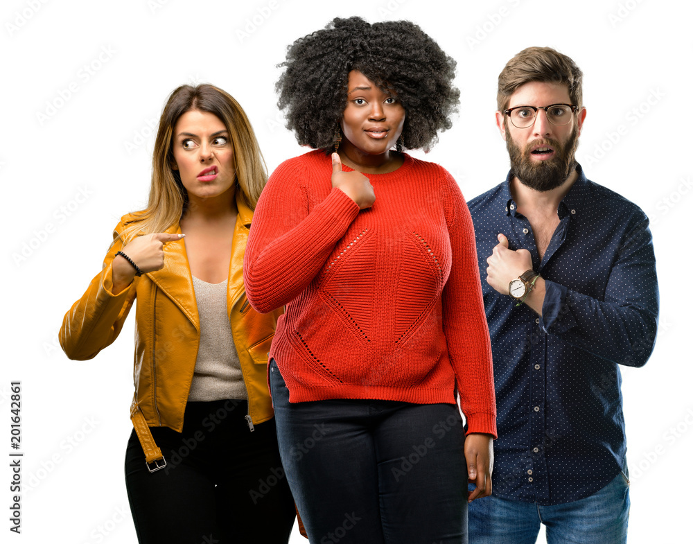 Group of three young men and women happy and surprised cheering expressing wow gesture, pointing with finger Group of three young men and women happy and surprised cheering expressing wow gesture, pointing with finger