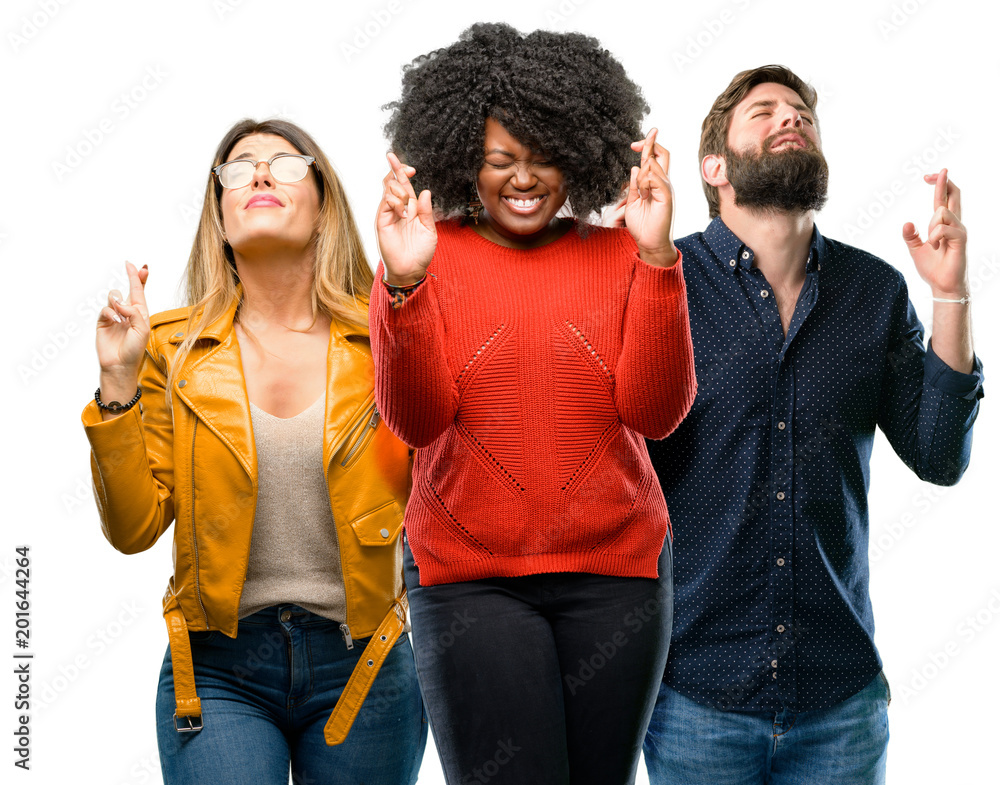 Group of three young men and women with crossed fingers asking for good luck Group of three young men and women with crossed fingers asking for good luck