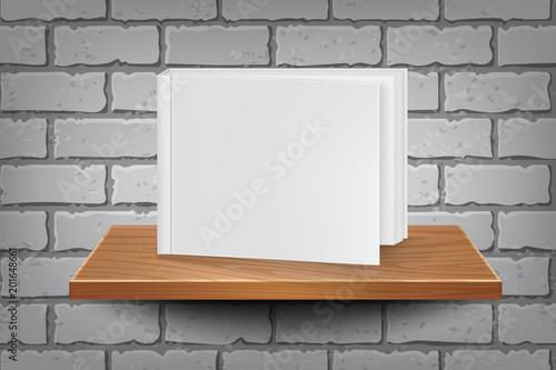 Empty book template on wooden shelf on a brick wall background.