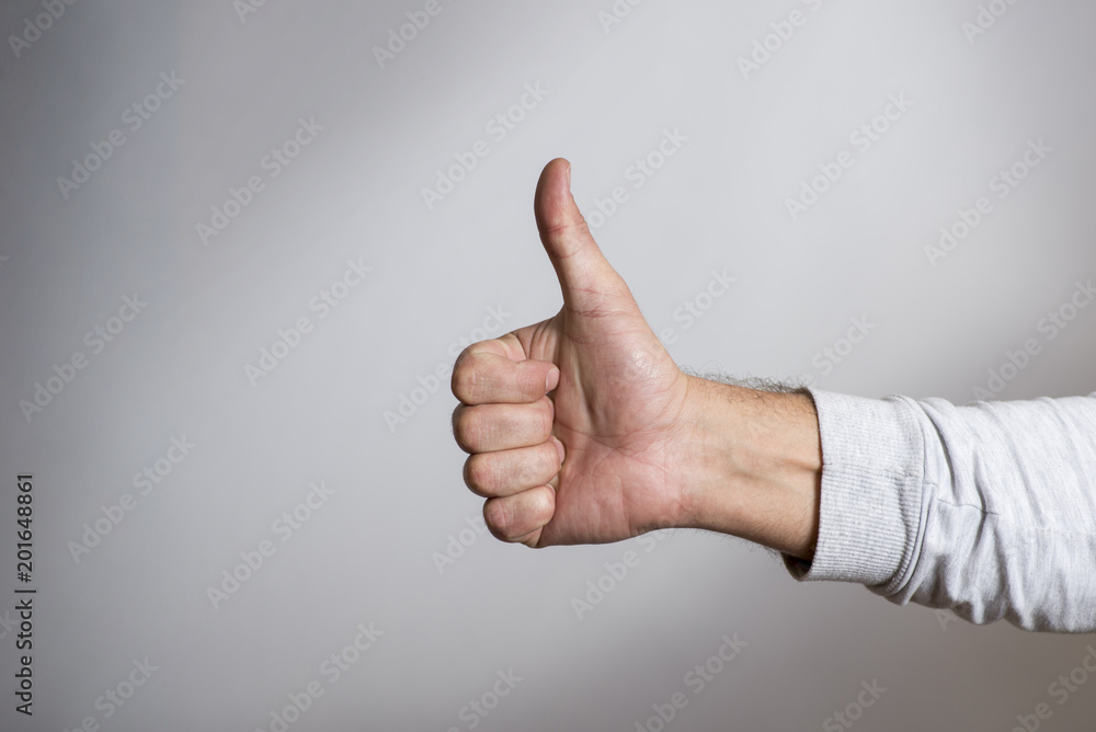 Hand with thumb upwards on a gray background. Man hand giving thumbs up