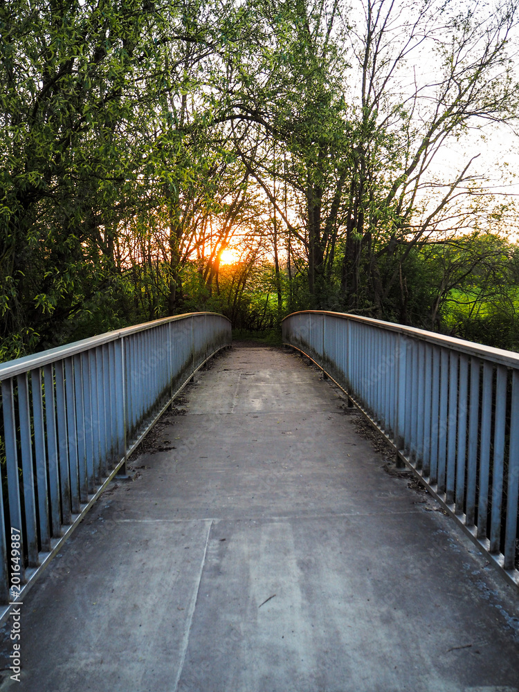 Sunset over a deserted metal bridge crossing the Leine river in the middle of the forrest, Laatzen, Hanover