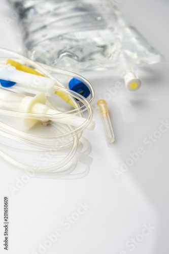 IV drip chamber, tubing, and bag of solution on a white table in a hospital.