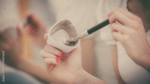 Female hand holding clay mud mask and brush. Skin care.