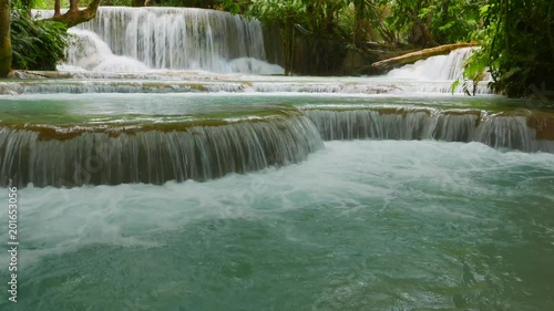 Paradise-like rain forest landscape with one of southeast Asia’s most beautiful waterfalls, the Kuang Si falls with cascading natural swimming pools. Gimbel-stabilized 4k pan footage. photo