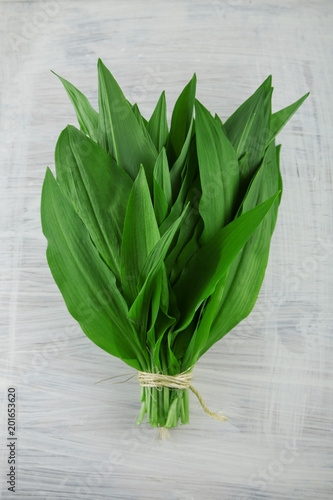 intensely fragrant fresh green wild garlic herbs decorated on rustic white wood plate kitchen background photo