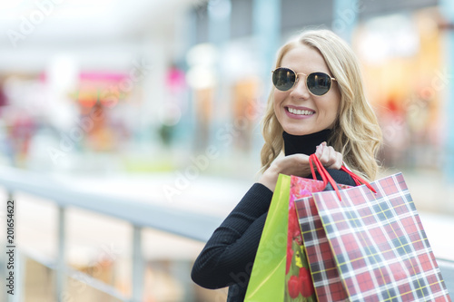 Beautiful stylish young woman in sunglasses with shopping bags, place for your text on the left