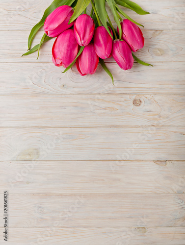 Fototapeta Naklejka Na Ścianę i Meble -  Bouquet of pink tulips on a light wooden background. View from above.