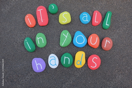 It's all in your hands, life and business conceptual sentence composed with multicolored stones over black sand