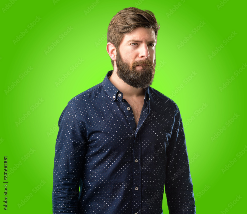 Obraz premium Young hipster man with big beard doubt expression, confuse and wonder concept, uncertain future over green background