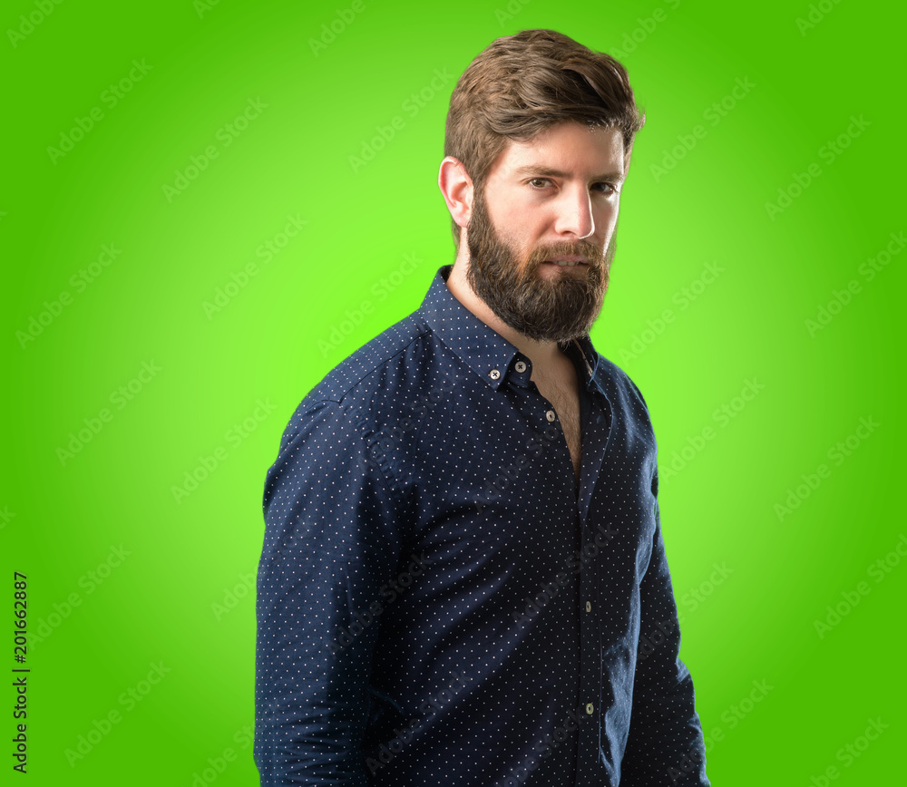 Obraz premium Young hipster man with big beard doubt expression, confuse and wonder concept, uncertain future over green background