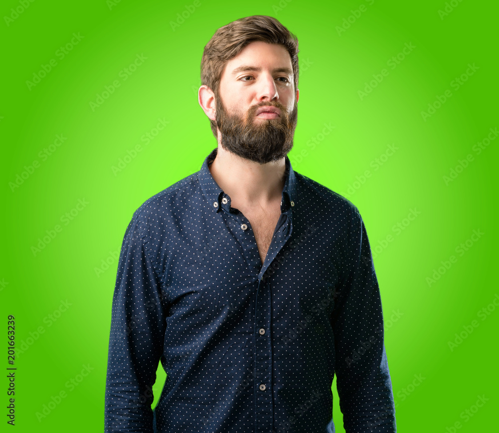 Obraz premium Young hipster man with big beard expressing love, blows kiss at camera, flirting over green background