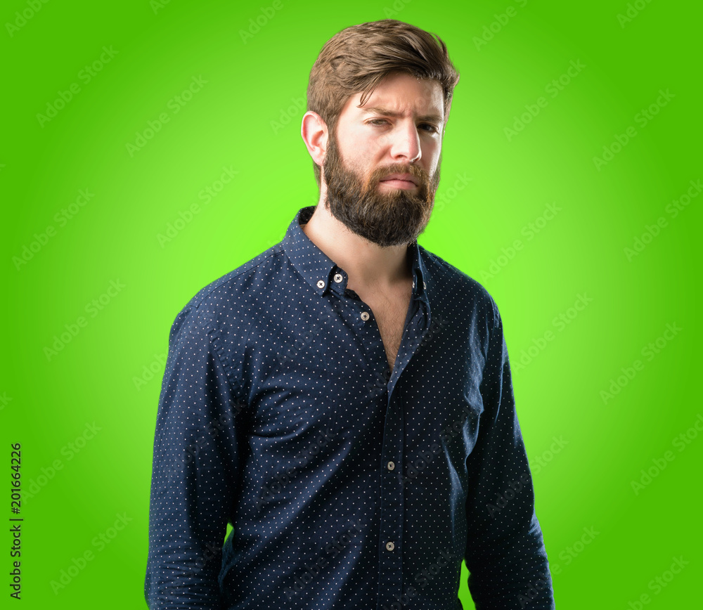 Young hipster man with big beard irritated and angry expressing negative emotion, annoyed with someone over green background Young hipster man with big beard irritated and angry expressing negative emotion, annoyed with someone over green background