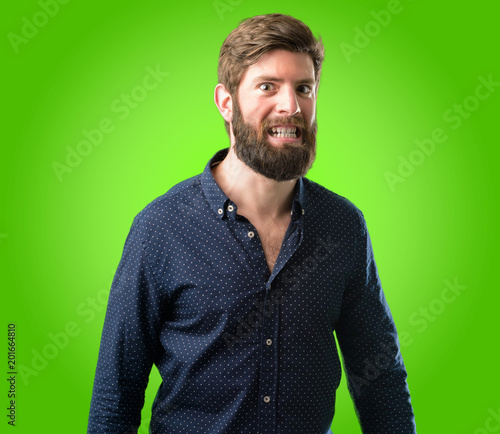 Young hipster man with big beard confident and happy with a big crazy smile laughing over green background