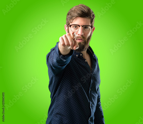 Young hipster man with big beard pointing to the front with finger over green background © Krakenimages.com