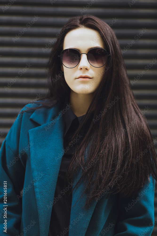 Beautiful brunette girl. Fashionable, stylish with black hair, in coats, jeans and sunglasses