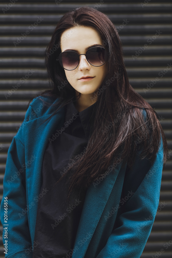 Beautiful brunette girl. Fashionable, stylish with black hair, in coats, jeans and sunglasses