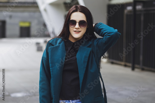 Beautiful brunette girl. Fashionable, stylish with black hair, in coats, jeans and sunglasses