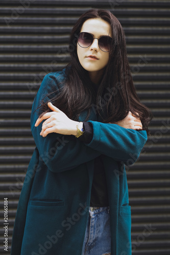 Beautiful brunette girl. Fashionable, stylish with black hair, in coats, jeans and sunglasses