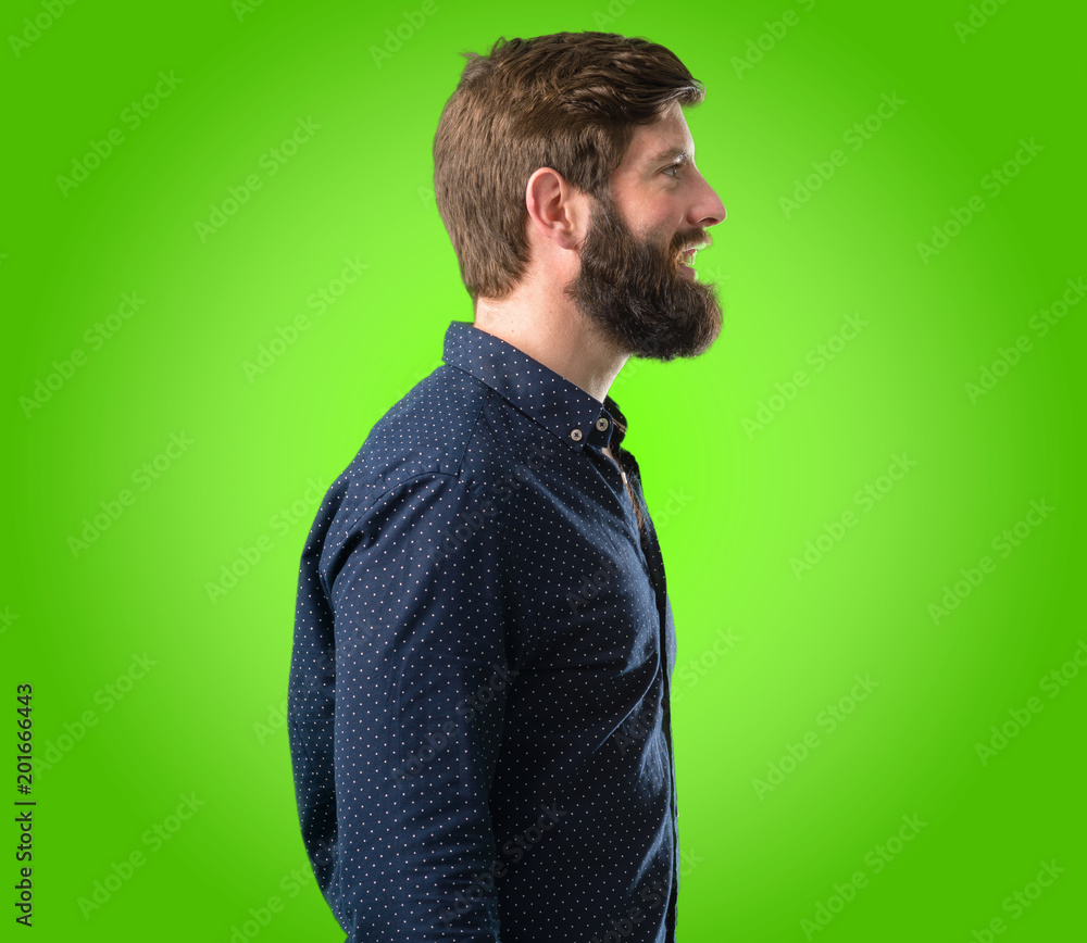 Young hipster man with big beard side view portrait over green background Young hipster man with big beard side view portrait over green background