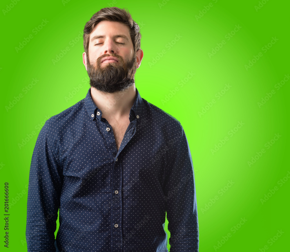 Fototapeta premium Young hipster man with big beard with sleepy expression, being overworked and tired over green background