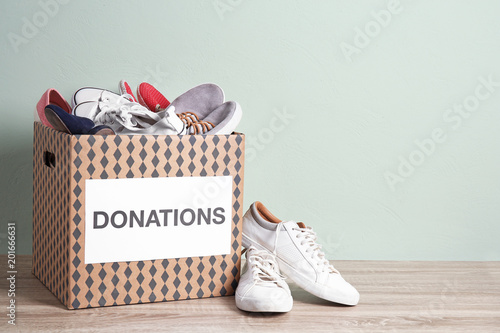 Photography Donation box with shoes on wooden table against color background
