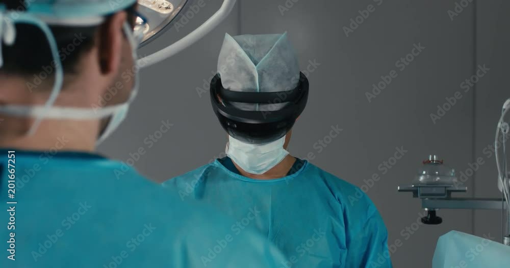 CU Portrait of surgeon using augmented reality holographic hololens headset while operating in modern operation theater. 4K UHD 60 FPS SLO MO CU Portrait of surgeon using augmented reality holographic hololens headset while operating in modern operation theater. 4K UHD 60 FPS SLO MO