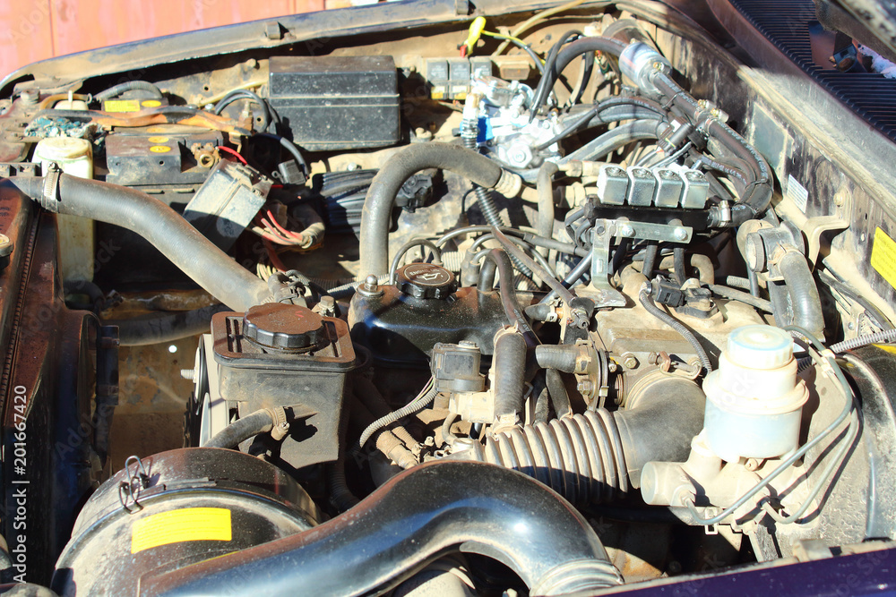 The car's engine is under the open hood. The car's engine is on gas. Close-up. Background.