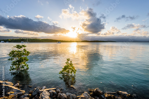 Port Douglas, Cairns, Queensland Australia: Beautiful summer sunset coast view to charming bay shore and blue Tasman Sea with a fishing boat yacht cruising and some colored clouds reflect