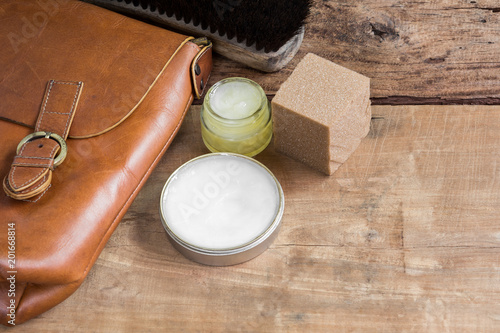 old genuine leather bag on wooden table prepare to clean and care with wax. maintenance concept.