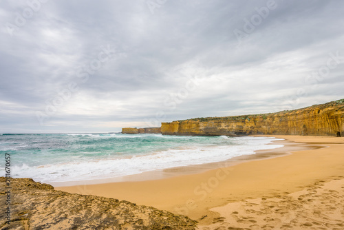 Cloudy sunny summer coast view to a beautiful sandy beach bay and rocky erosion sand limestone cliff of Great Ocean Road, walking at Loch Ard Gorge, Port Campbell National Park, Victoria/ Australia