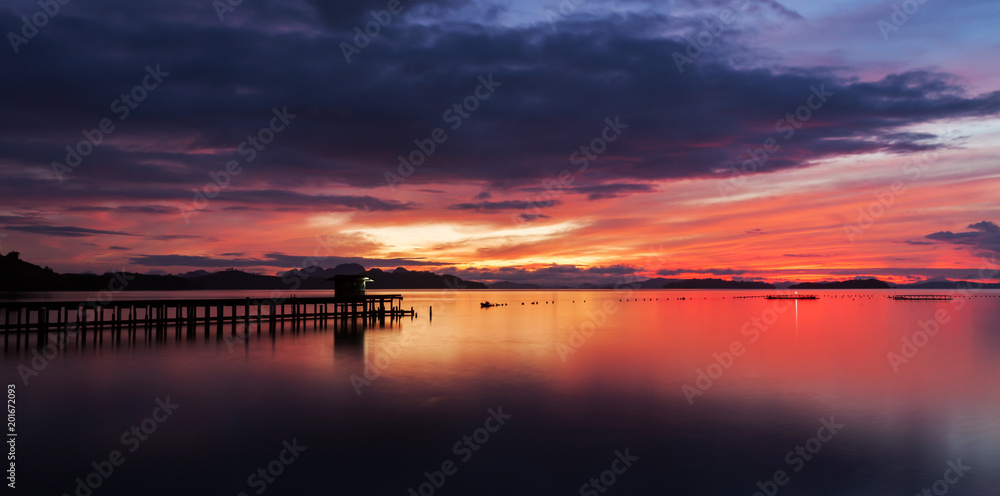 old small jetty in to the sea in Long exposure image of dramatic sunset or sunrise,sky and clouds over tropical sea scenery landscape.
