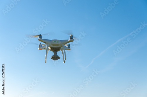 Fototapeta Naklejka Na Ścianę i Meble -  White drone in flight on blue sky background