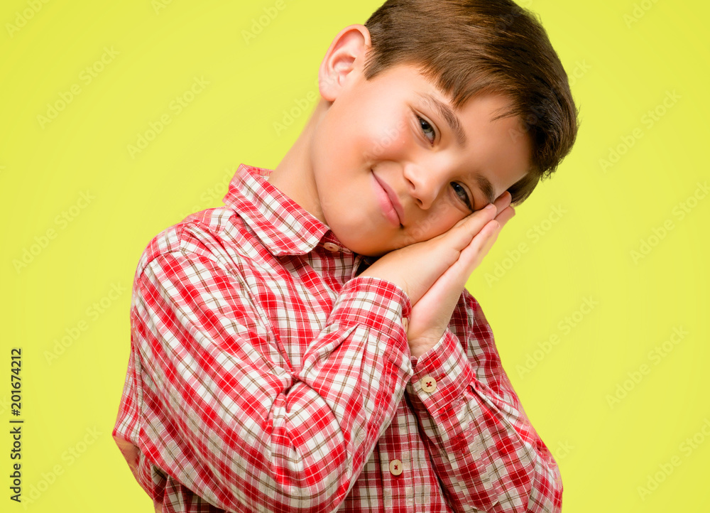 Handsome toddler child with green eyes tired and bored, tired because of a long day overworking over yellow background Handsome toddler child with green eyes tired and bored, tired because of a long day overworking over yellow background