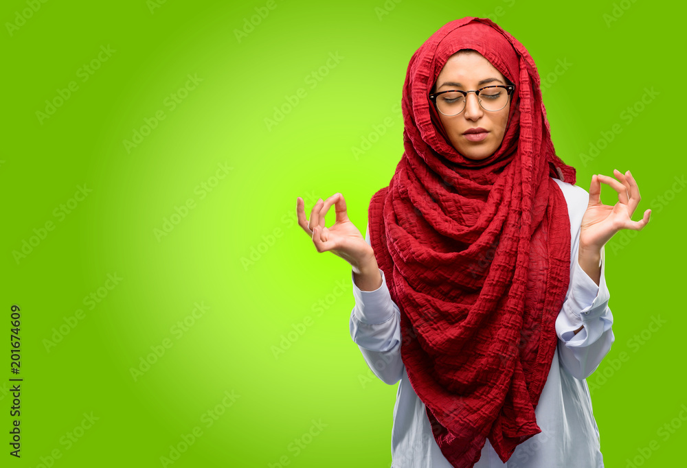 Young arab woman wearing hijab doing ok sign gesture with both hands expressing meditation and relaxation Young arab woman wearing hijab doing ok sign gesture with both hands expressing meditation and relaxation