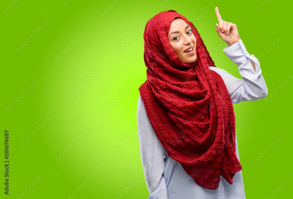 Young arab woman wearing hijab happy and surprised cheering expressing wow gesture pointing up Young arab woman wearing hijab happy and surprised cheering expressing wow gesture pointing up