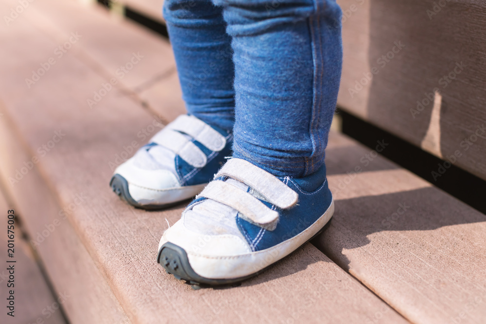 Toddler boy wearing his blue sneakers outside