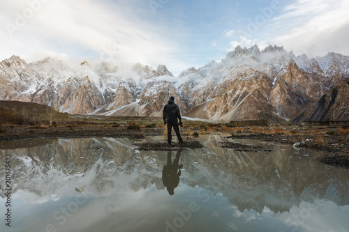Photographer looking at Passu Cathedral mountain in Pakistan and reflection on the water